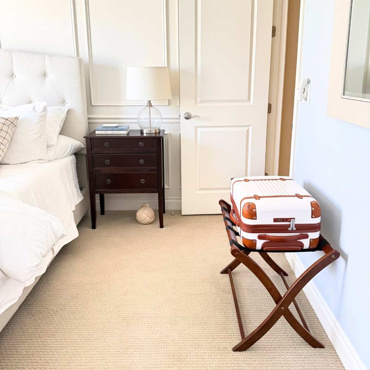 luggage on top of a wood luggage rack in a guest bedroom