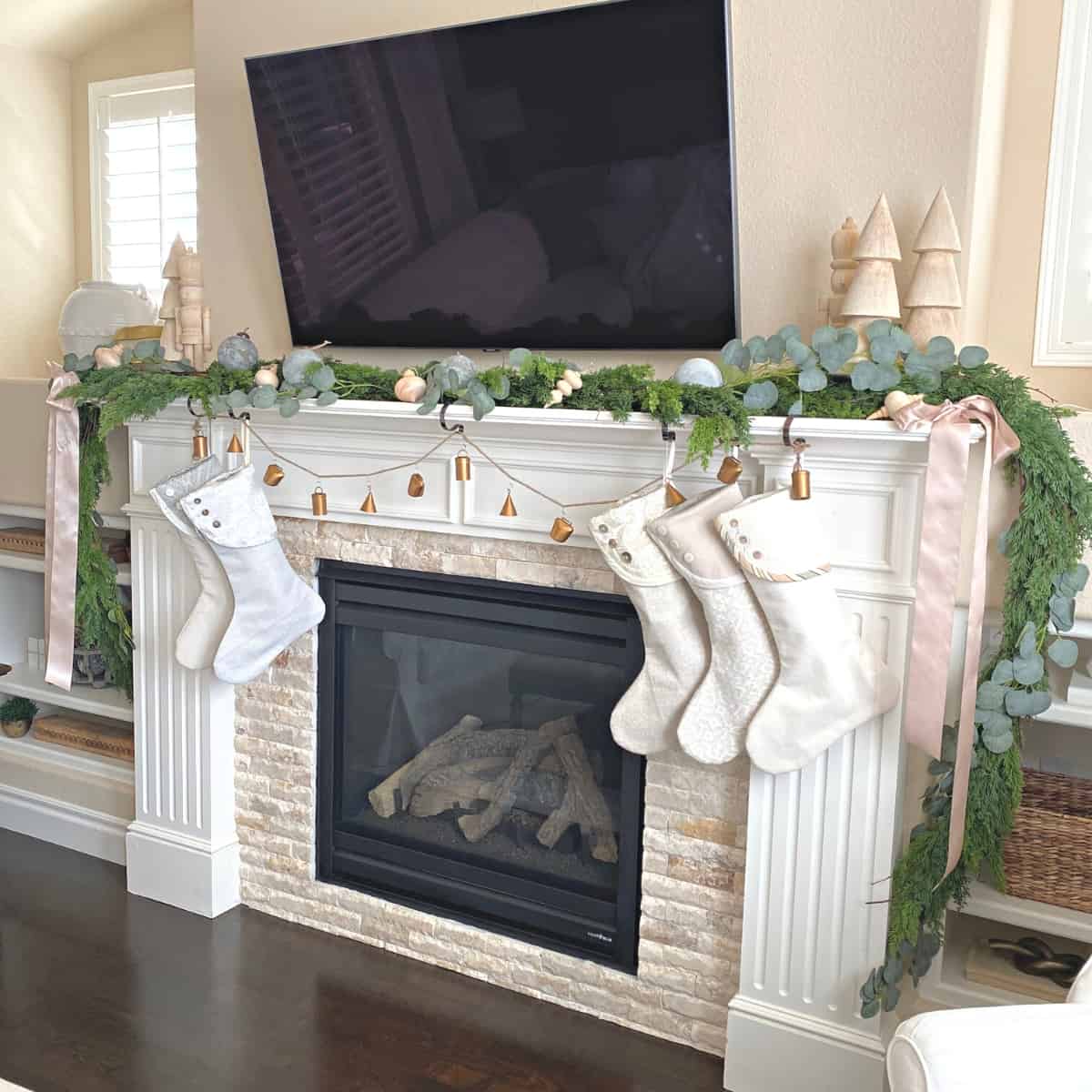 Fireplace mantel decorated for Christmas with greenery garland, stockings and ornaments