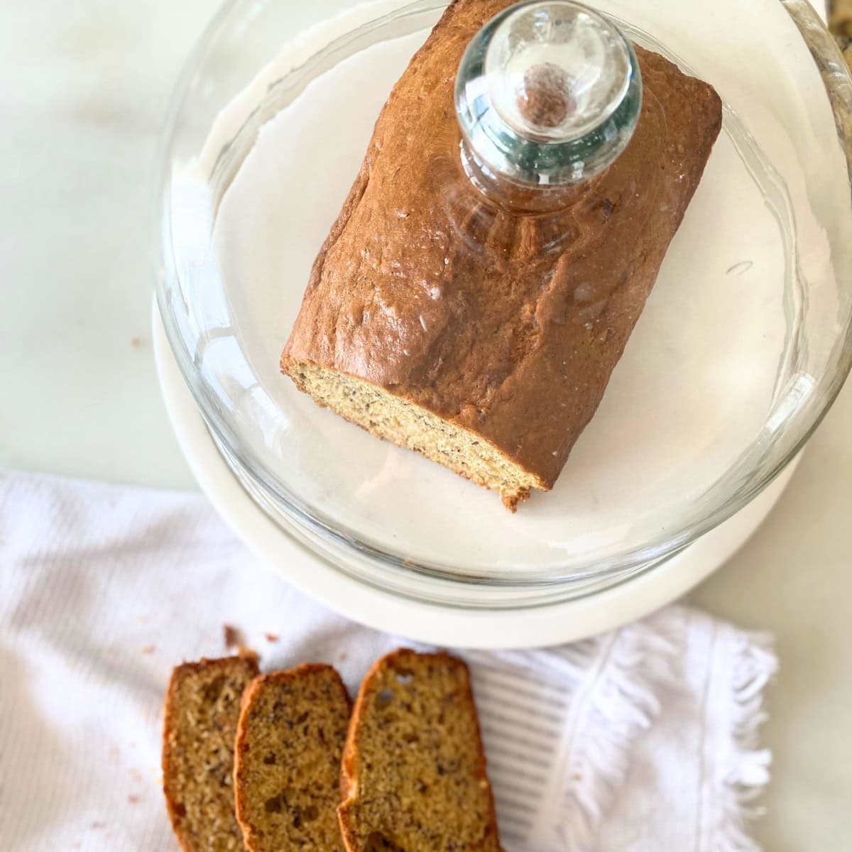 banana bread on marble cake stand with glass dome