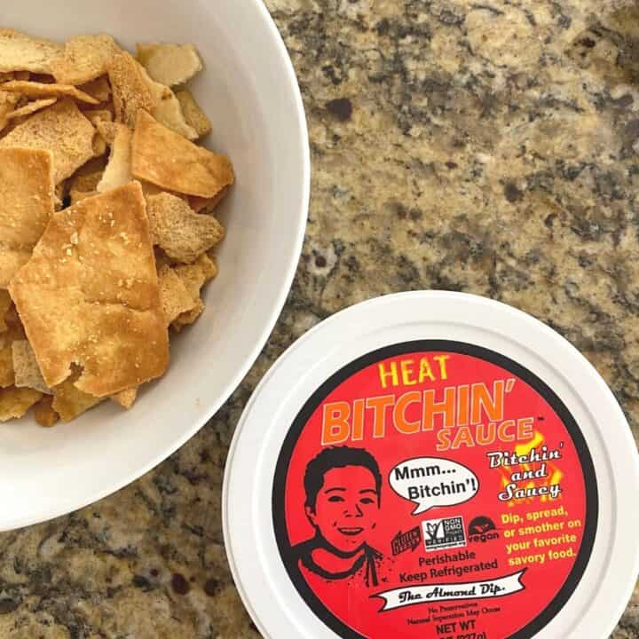 Bowl of pita chips sits next to the Heat Bitchin' Sauce atop a granite kitchen counter.