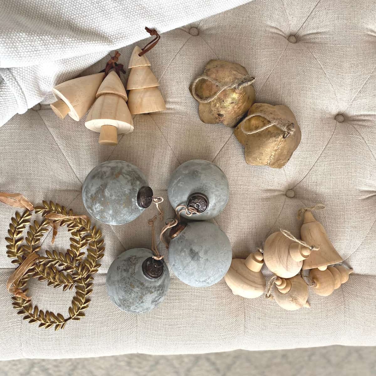 Neutral Christmas ornaments on a tufted ottoman