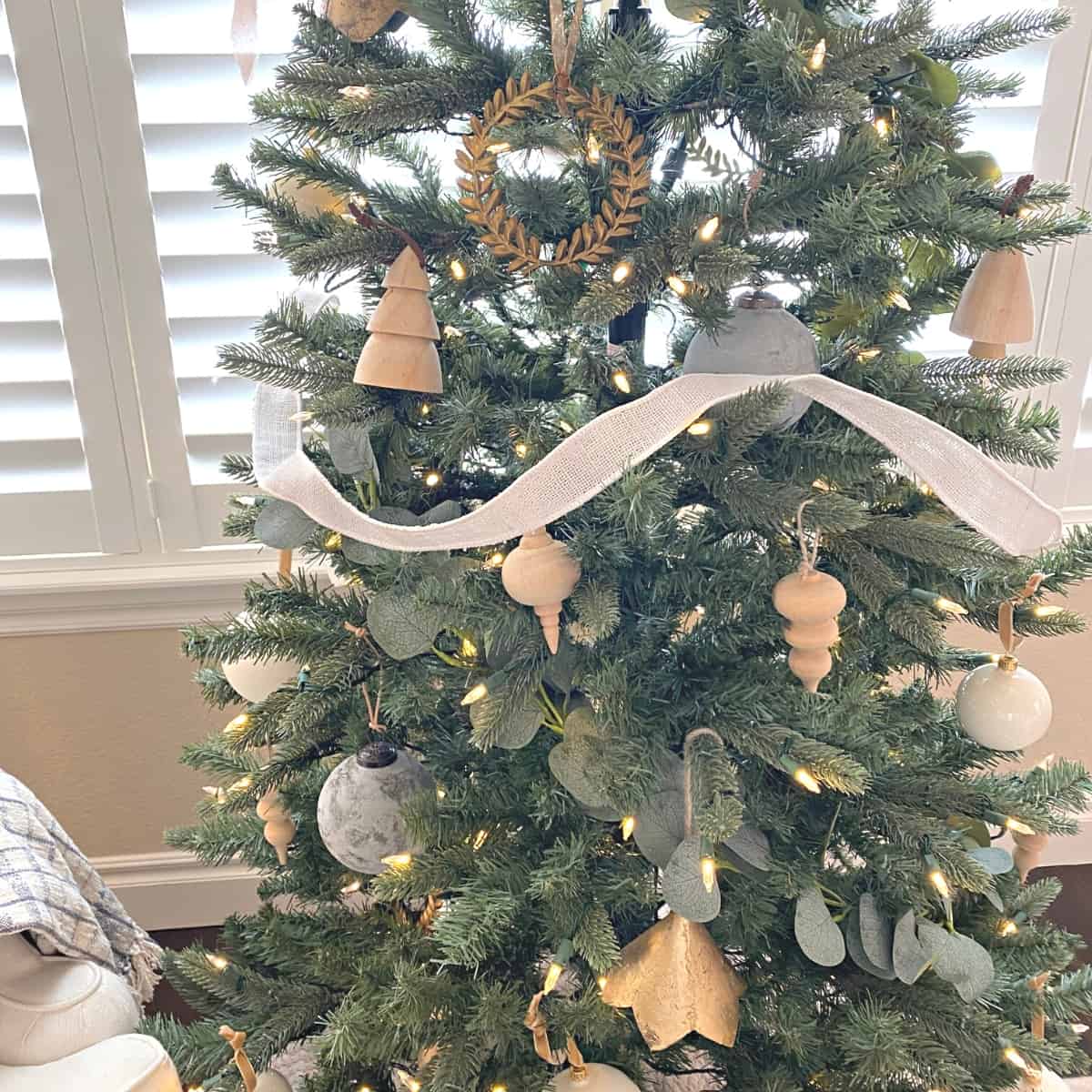 Mid-Christmas tree decorated in neutral ornaments, with white jute ribbon as garland