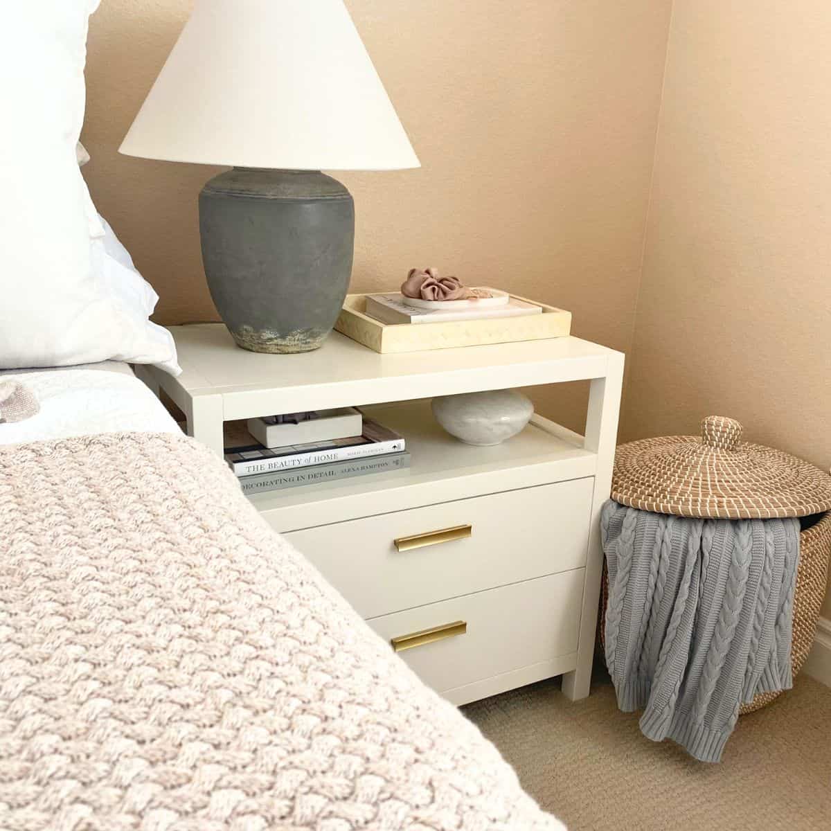 tall basket with blanket next to a white nightstand decorated