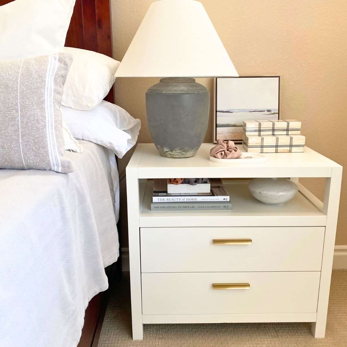 nightstand decorated with wall art, stacked books and boxes