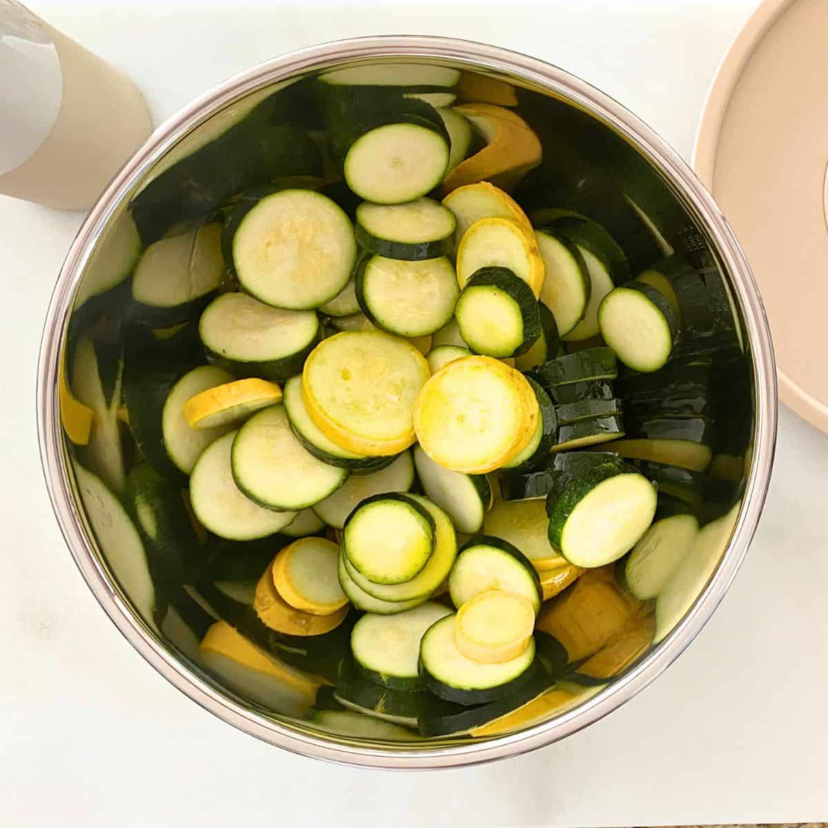 sliced vegetables in stainless steel mixing bowl with olive oil