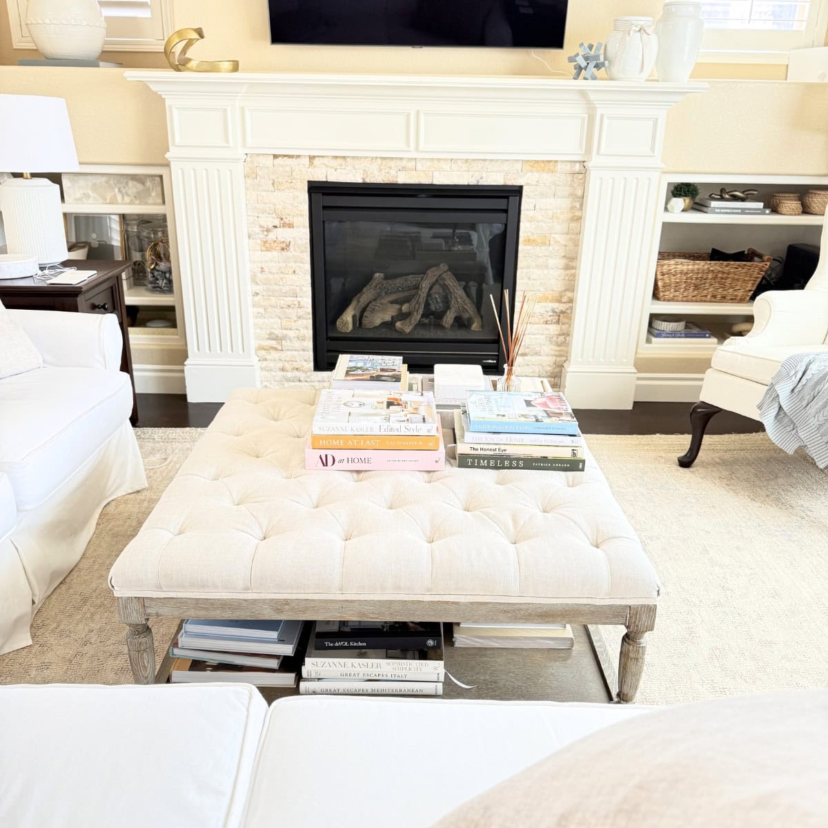 linen tufted ottoman styled with stacked coffee table books