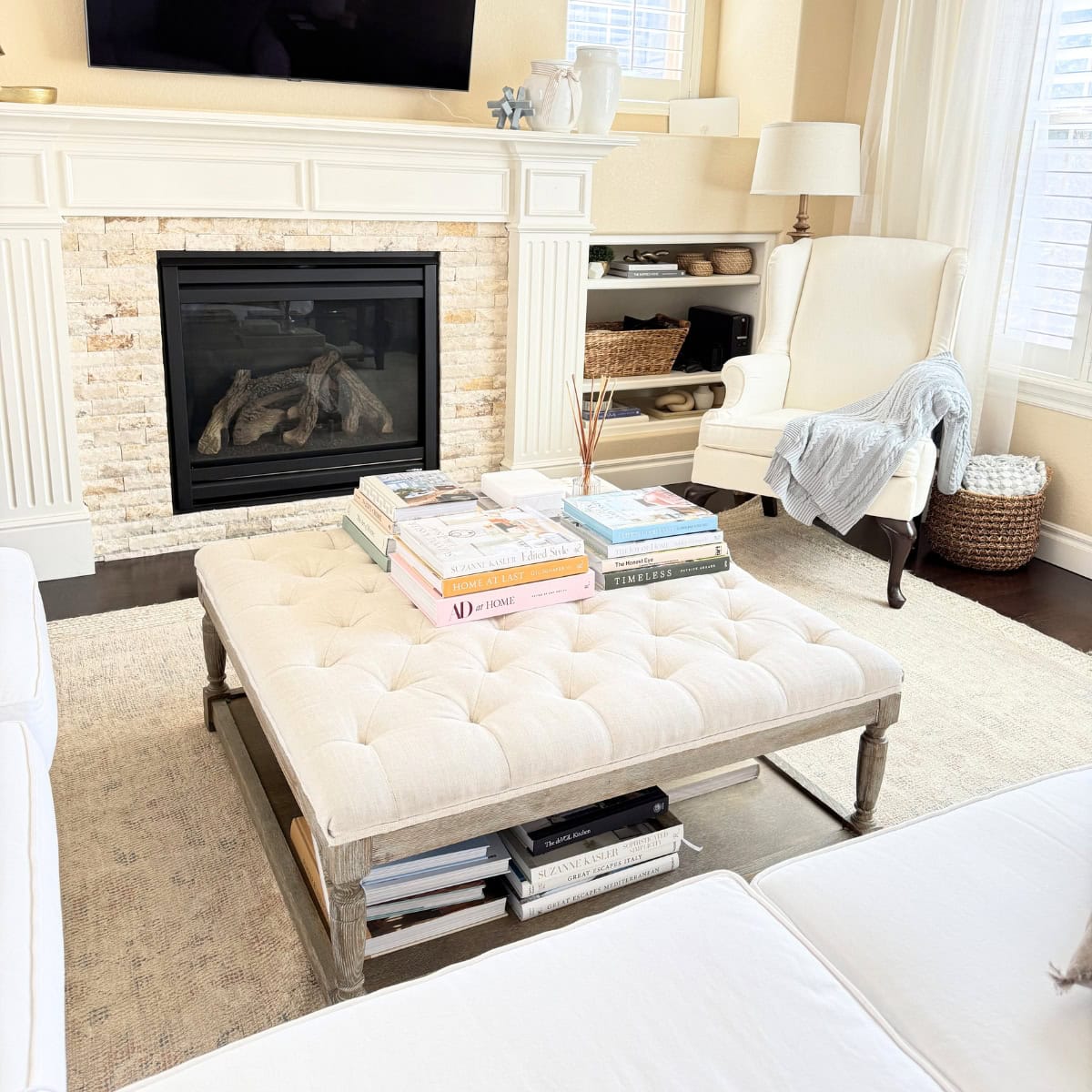 linen tufted ottoman styled with stacked coffee table books