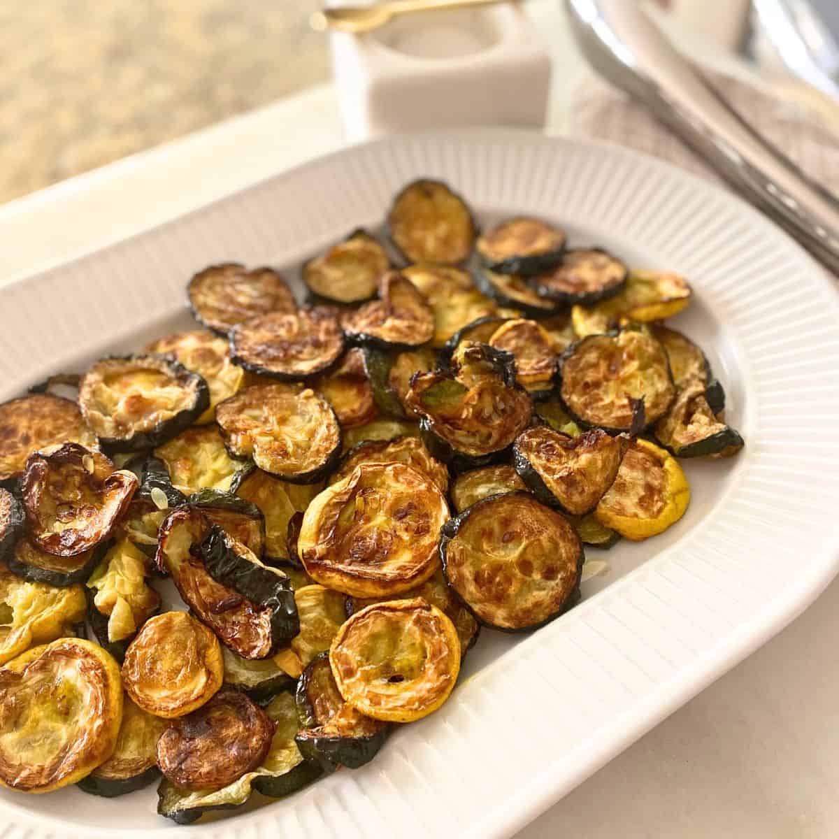 oven roasted zucchini and yellow squash on white porcelain serving platter