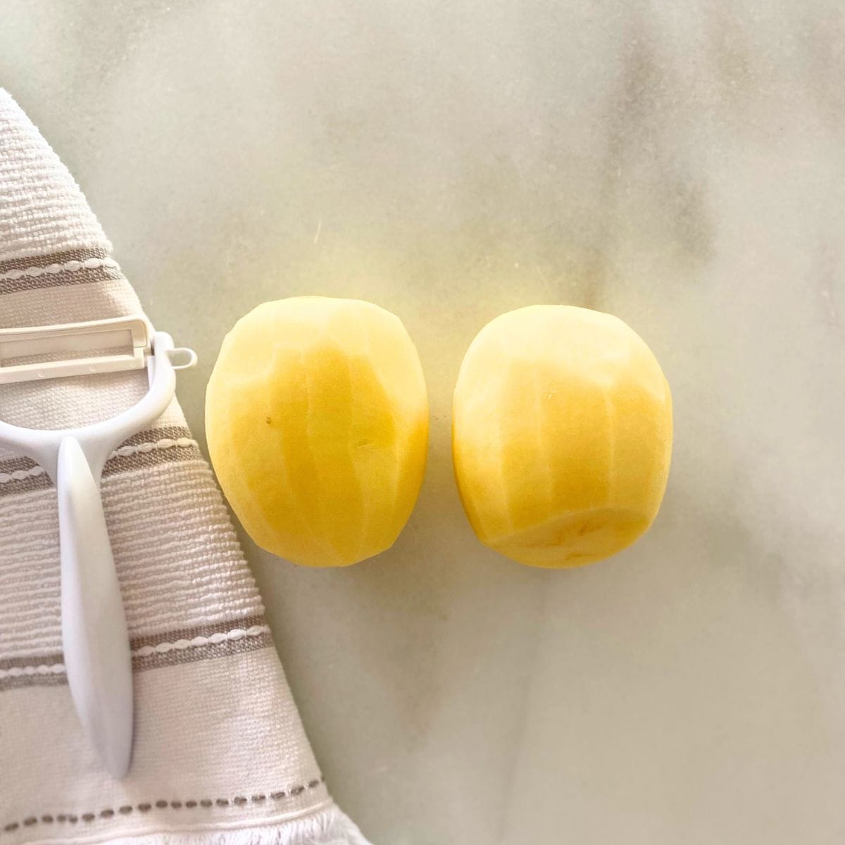 two yellow potatoes peeled