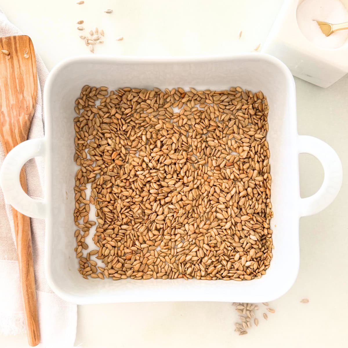 small white porcelain square baker with roasted sunflower seeds in it