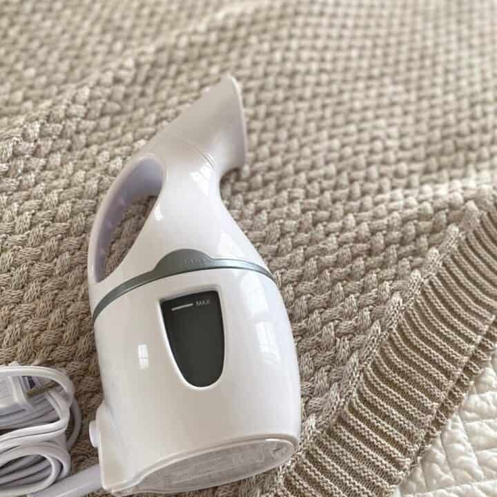 Portable white steamer on a brown heathered blanket.