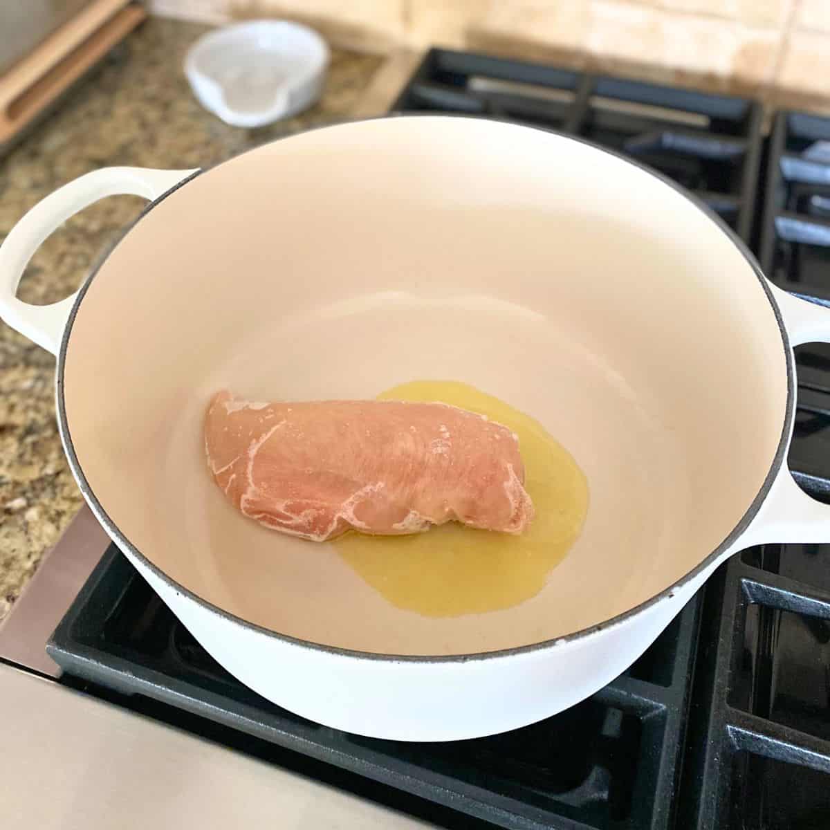 raw chicken in white enameled cast iron pot