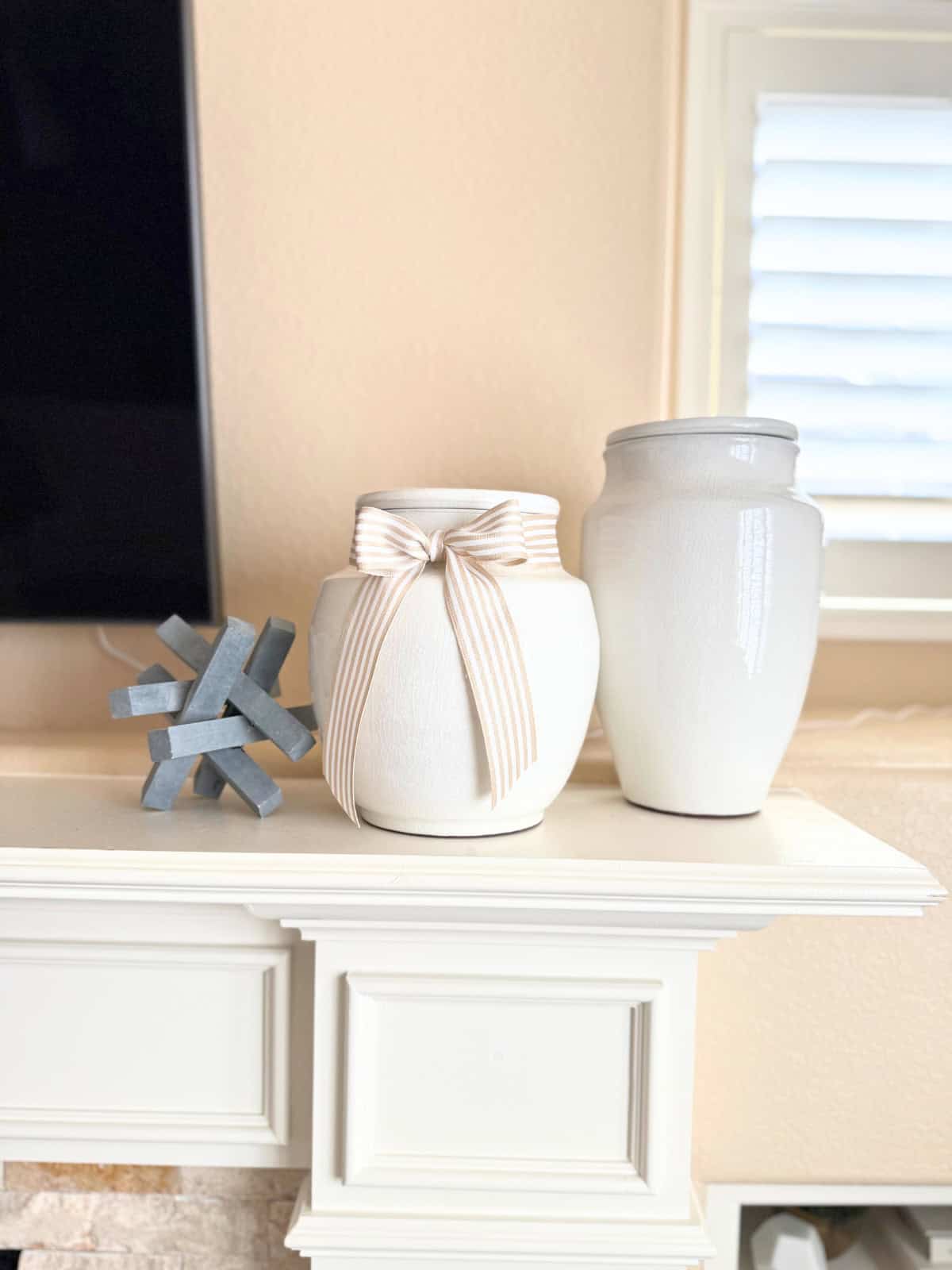 two pretty white vases and blue soapstone object on mantel