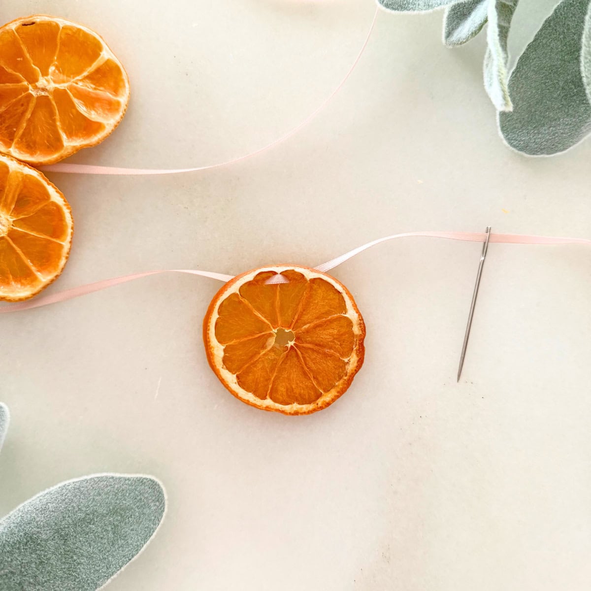 process threading ribbon through orange slice for garland