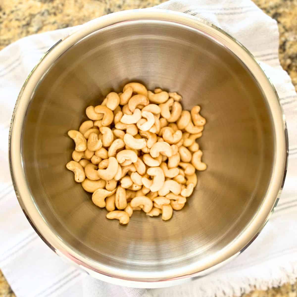 Raw cashews in a stainless steel mixing bowl