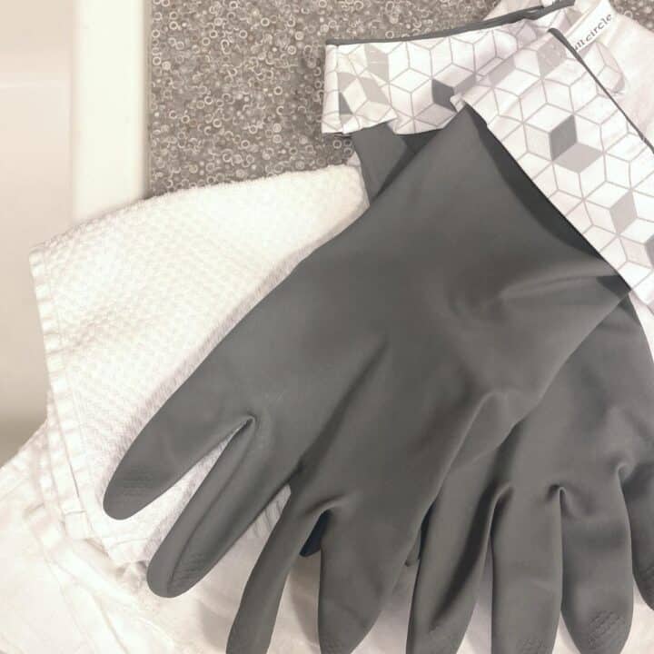 Reusable gray cleaning gloves atop a white cloth