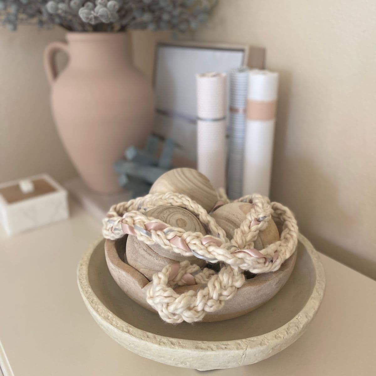 braided yarn garland with ribbon in a wood bowl