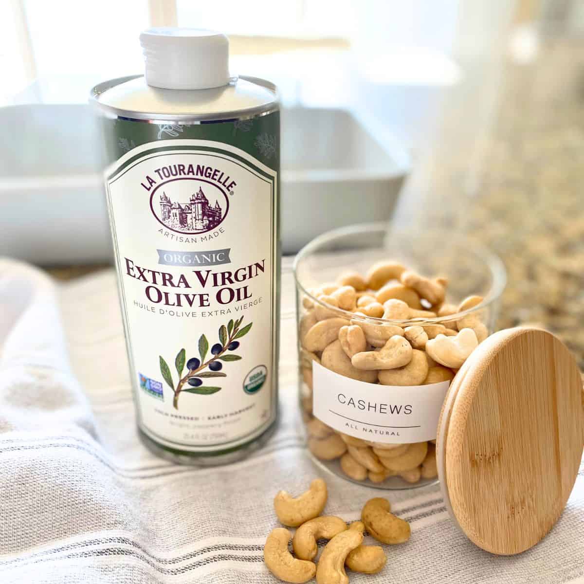 Ingredients displayed on a countertop for roasted cashews, consisting of olive oil and raw cashews