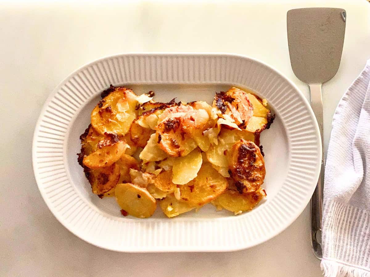 Scalloped potatoes served on a white porcelain oval serving platter