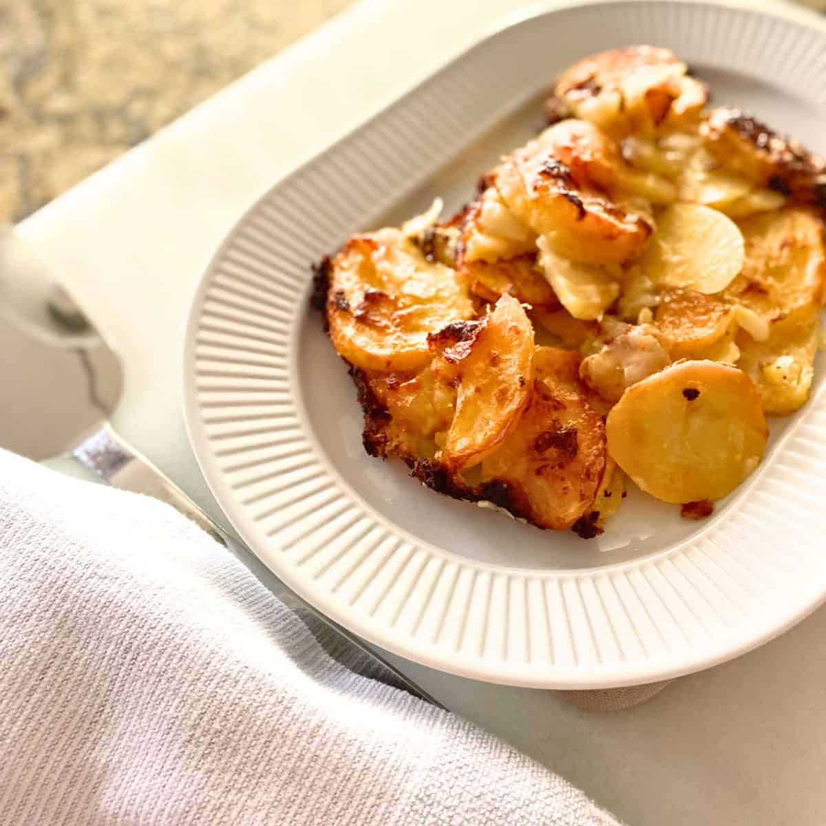 Scalloped potatoes served on a white porcelain oval serving platter