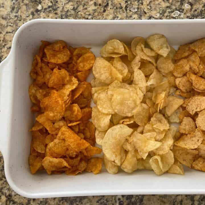 Three different flavors of potato chips served in a white rectangular roasting pan closeup