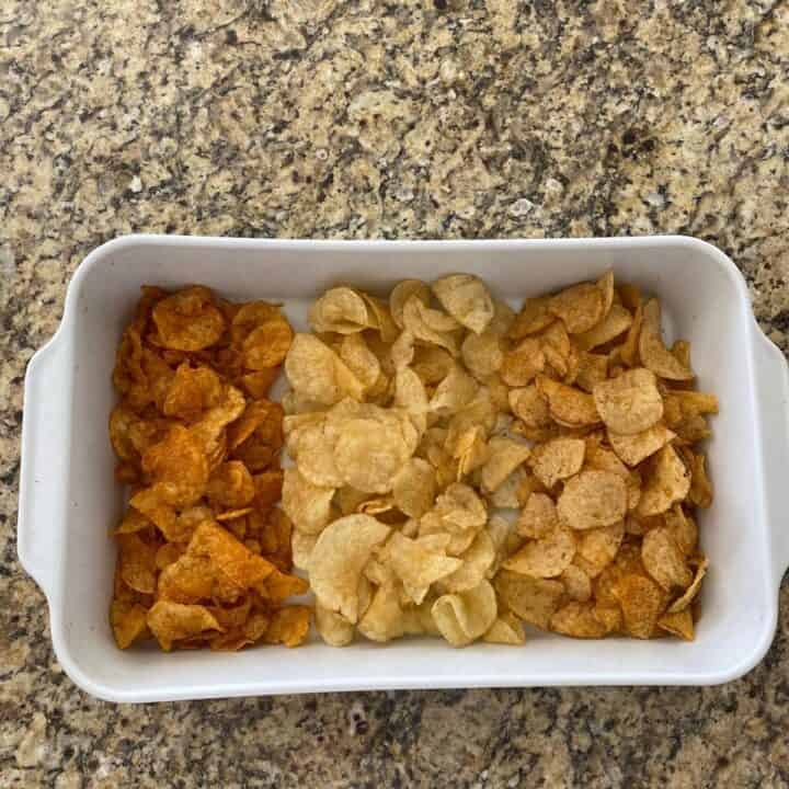 Three different flavors of potato chips served in a white rectangular roasting pan from above