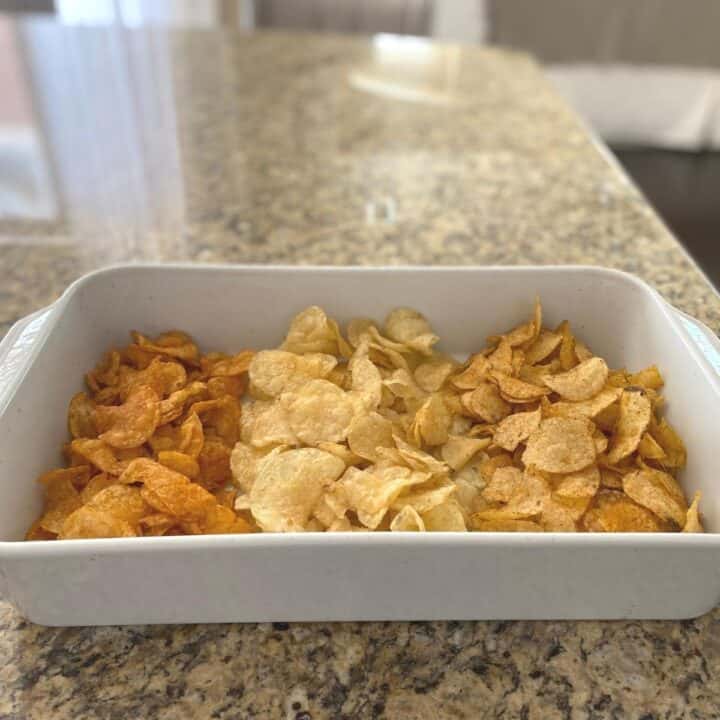 Three different flavors of potato chips served in a white rectangular roasting pan