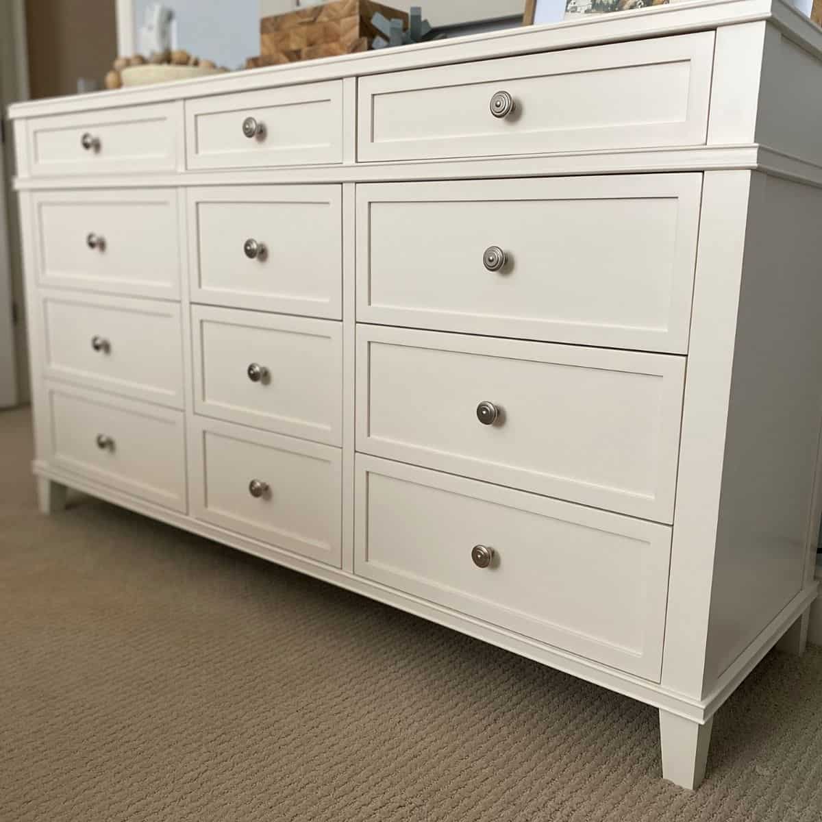 Long white twelve drawer dresser with round nickel hardware. Dresser is the Clara dresser from Pottery Barn.