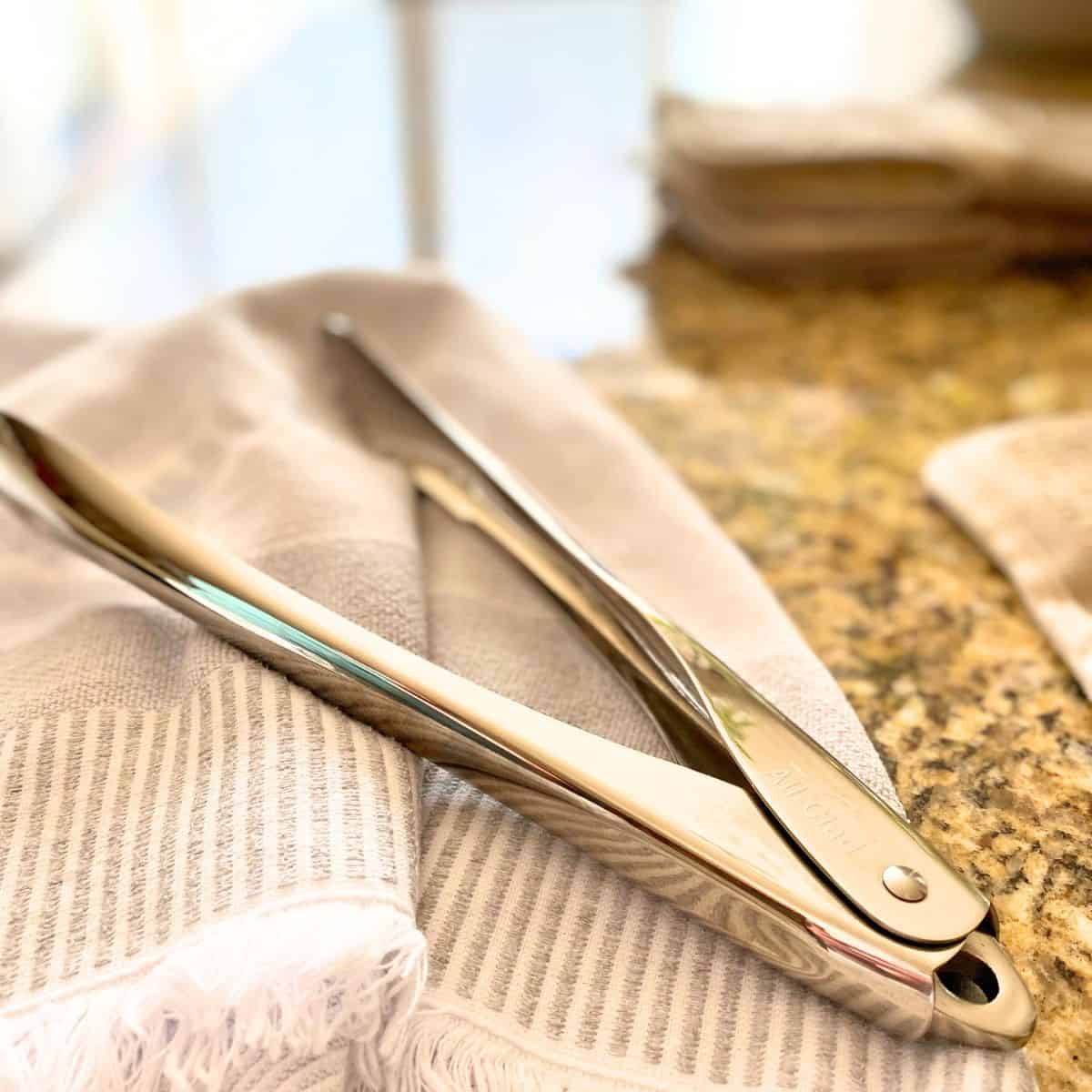 Stainless steel kitchen serving tongs on a kitchen counter