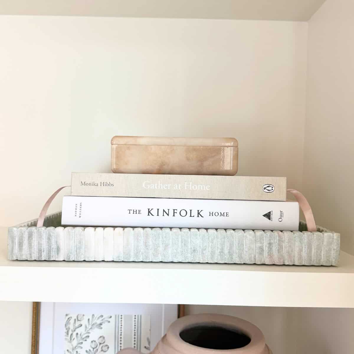 books stacked in marble tray with small beige marble box atop