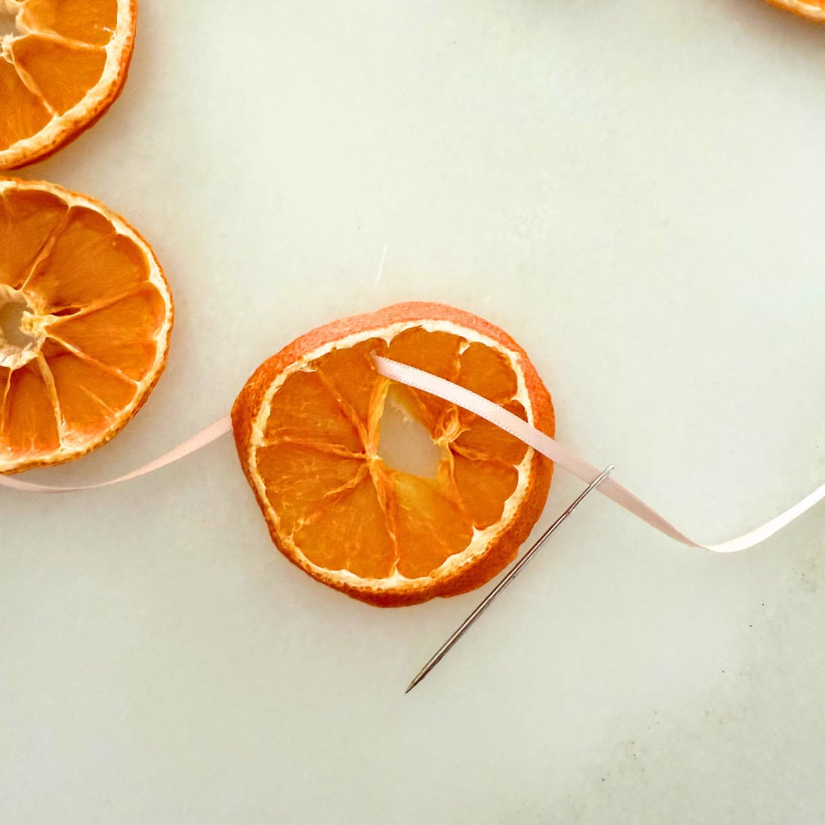 process threading ribbon through orange slice for garland