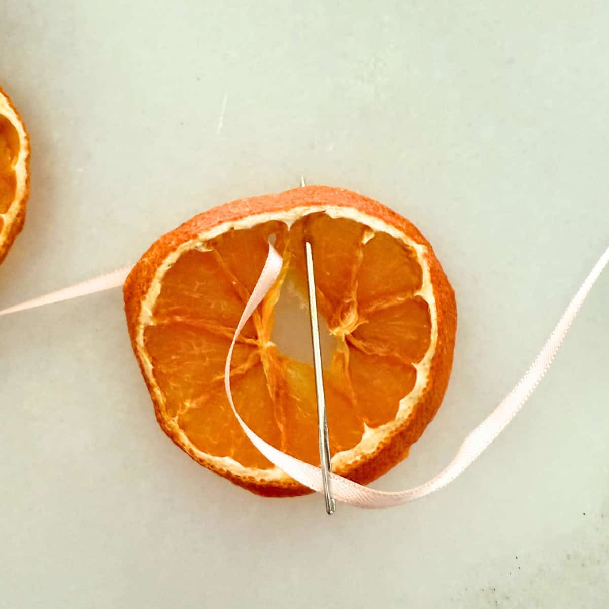 process threading ribbon through orange slice for garland