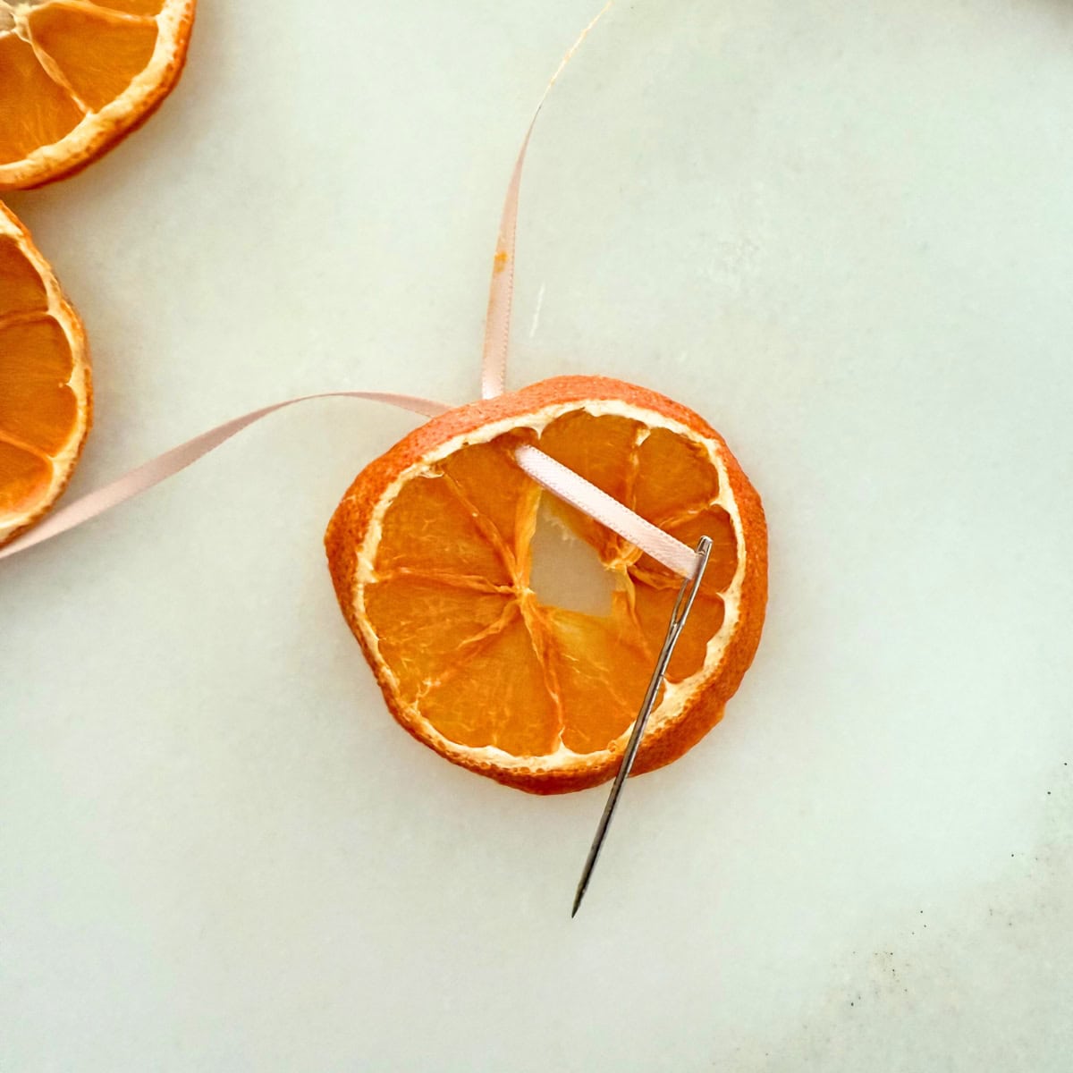 process threading ribbon through orange slice for garland