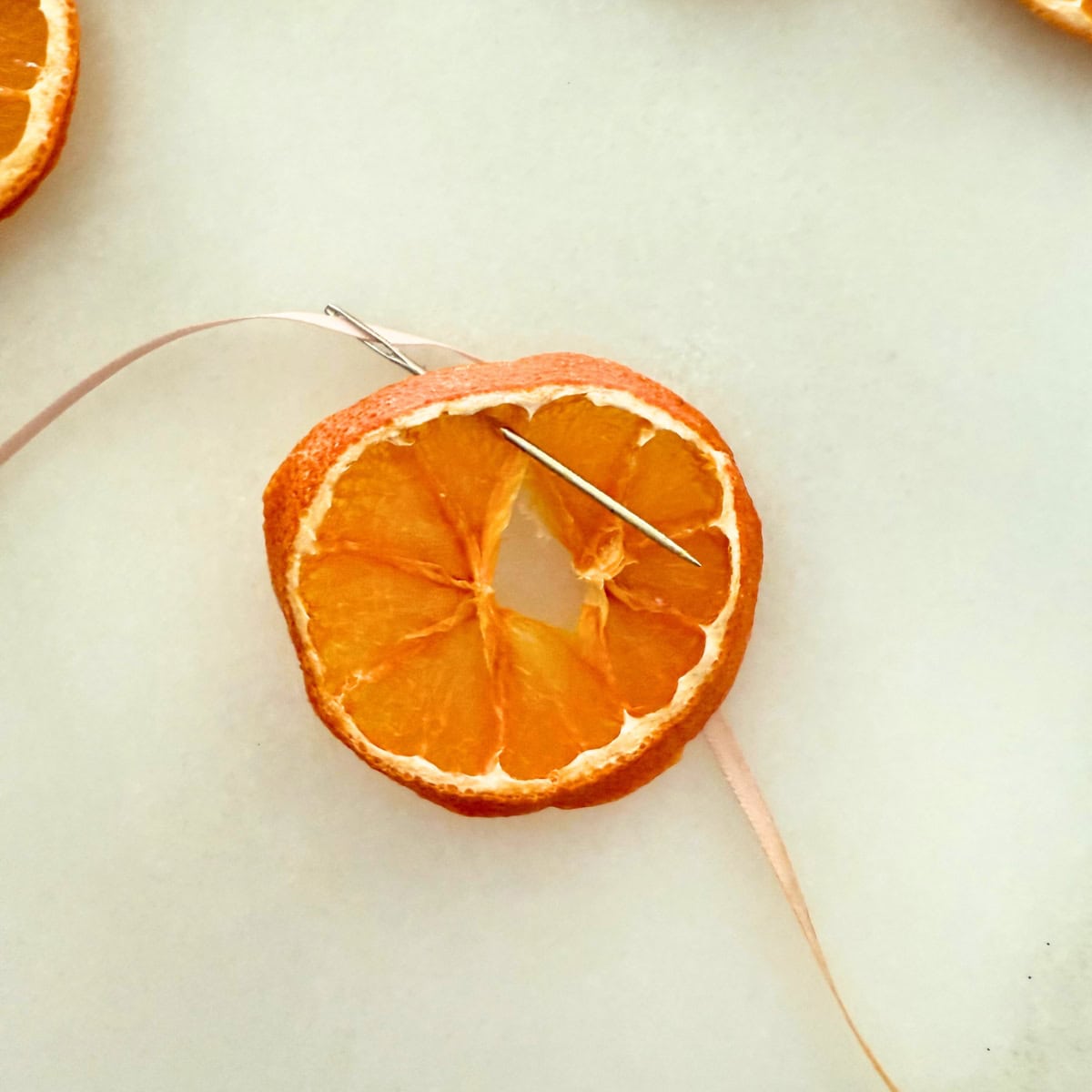 process threading ribbon through orange slice for garland