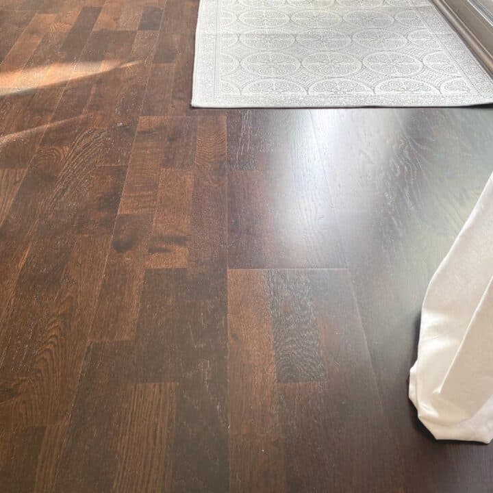 Dark hardwood floors with a neutral, black and beige patterned rug at the top right, showing dark hardwood as a timeless interior design element