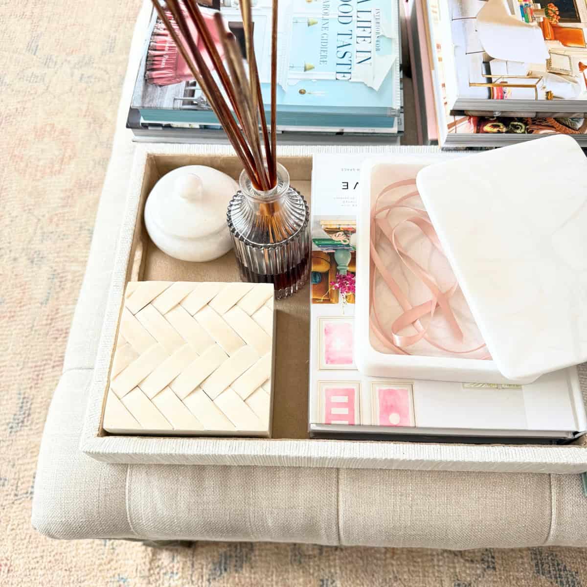 tray with decor surrounded by books on ottoman