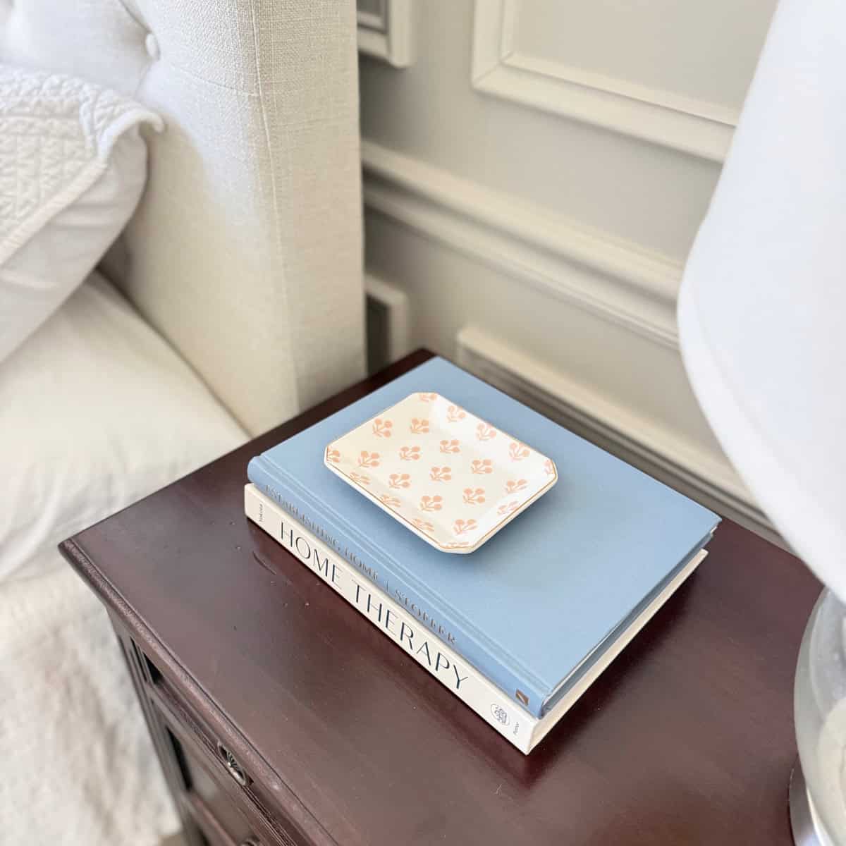 block print trinket dish atop two books on a dark wood nightstand