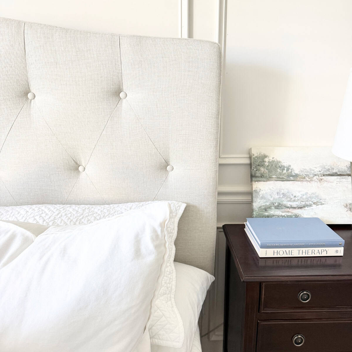 neutral tufted upholstered headboard next to nightstand