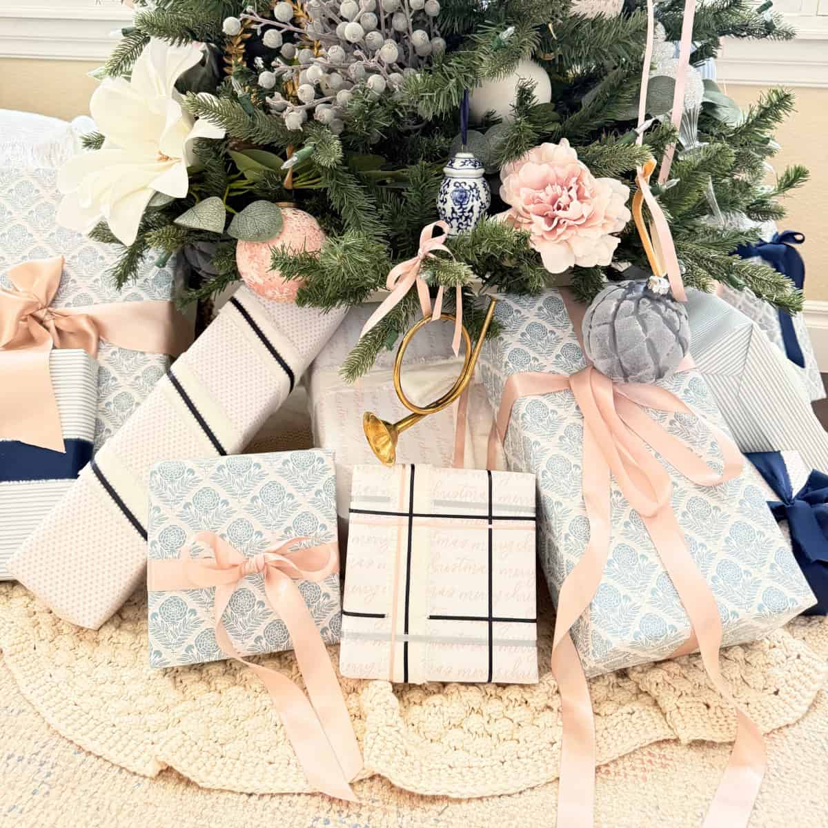 presents wrapped in blue white and pink paper under a tree