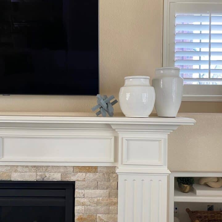 Partial fireplace mantel and TV overhead. Two white vases sit off to the side, with a blue soapstone decorative accessory.