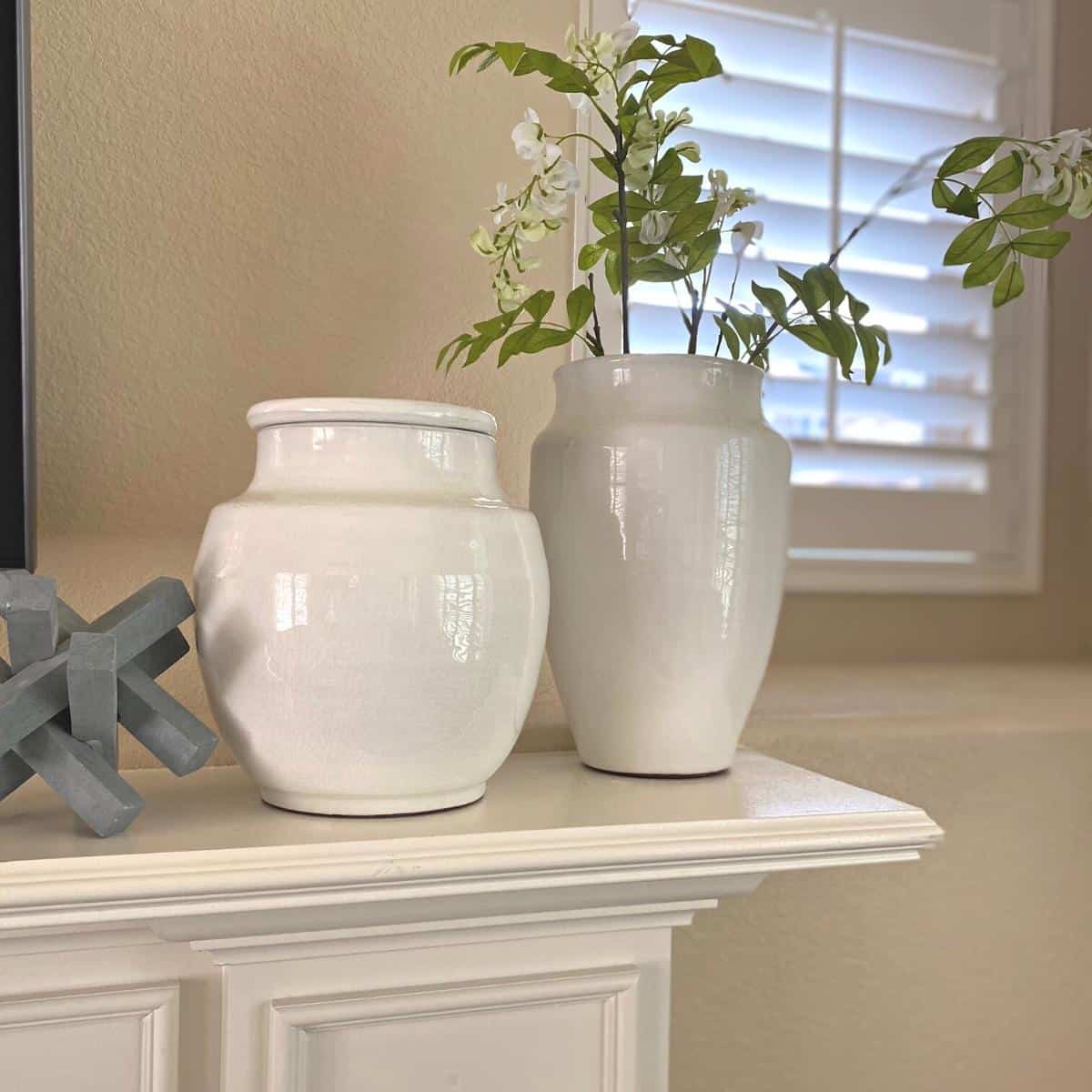 Two white terracotta vase jars on a fireplace mantle