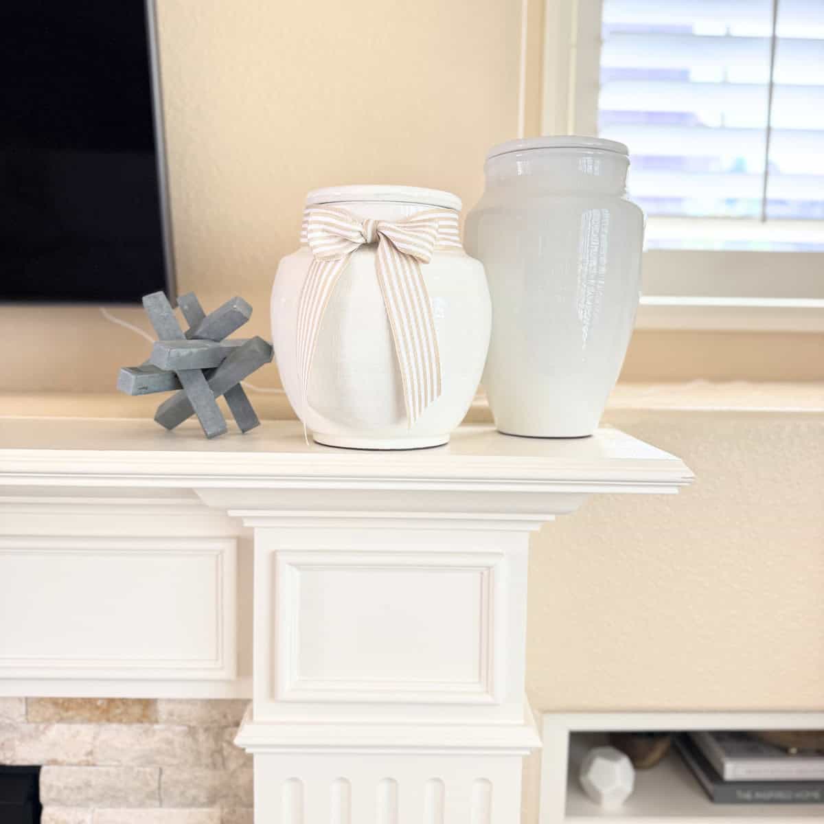 two white terracotta vases styled on a fireplace mantel
