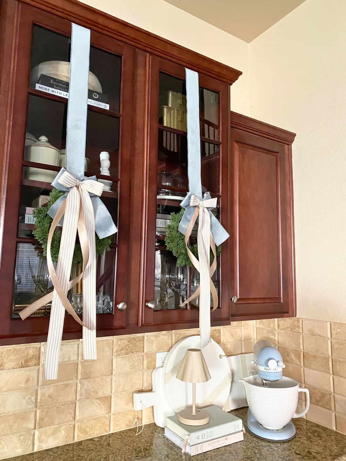 wreaths with long ribbon hanging on cabinets